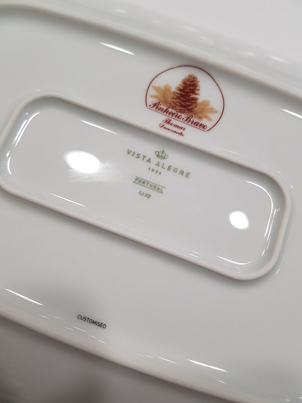 Parte de prato de porcelana branco com marcas e logótipos no verso