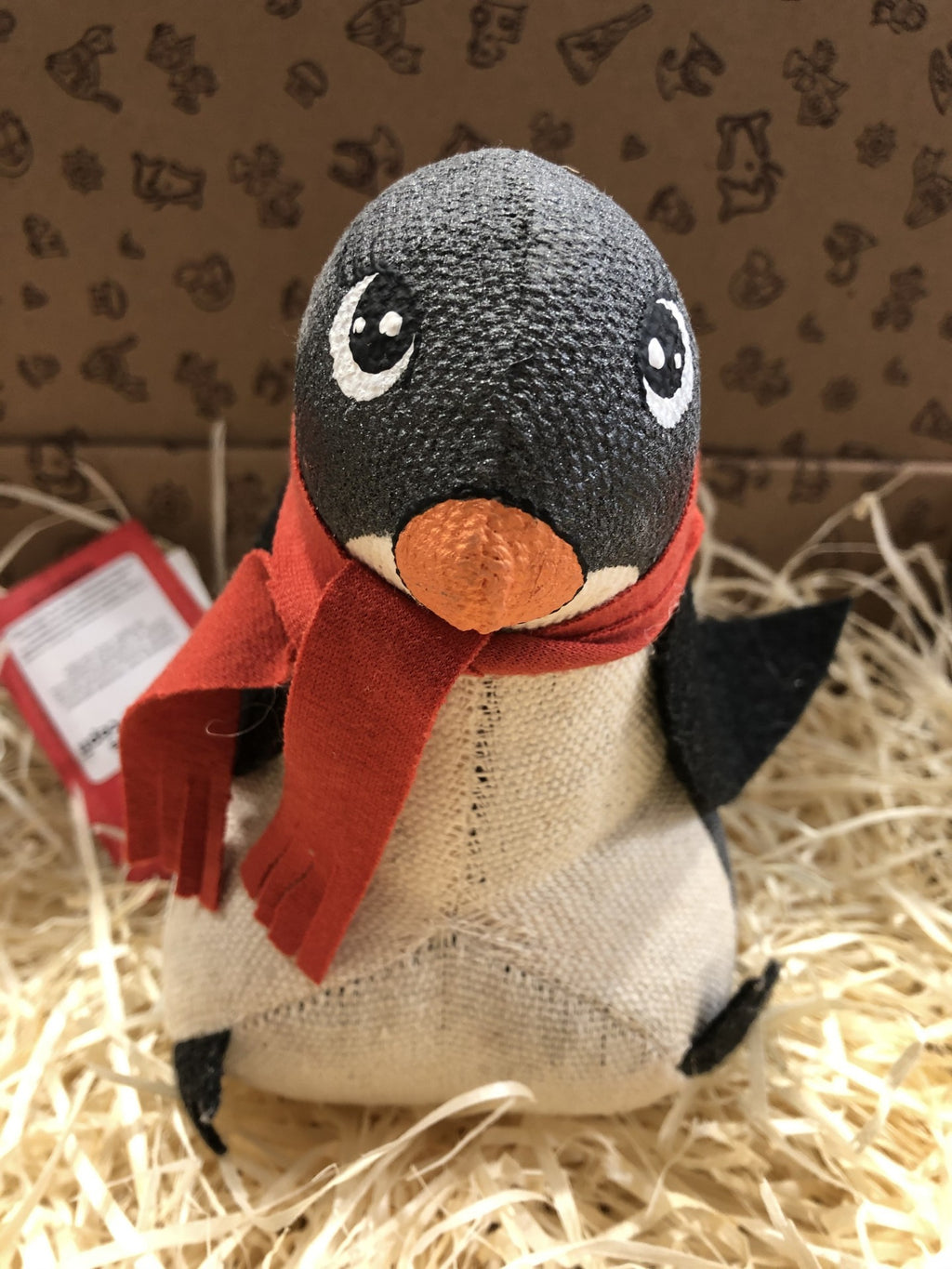 Pelúcia de pinguim com cachecol vermelho