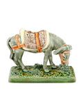 Figura decorativa de burro em cerâmica com sela castanha e bege a comer erva