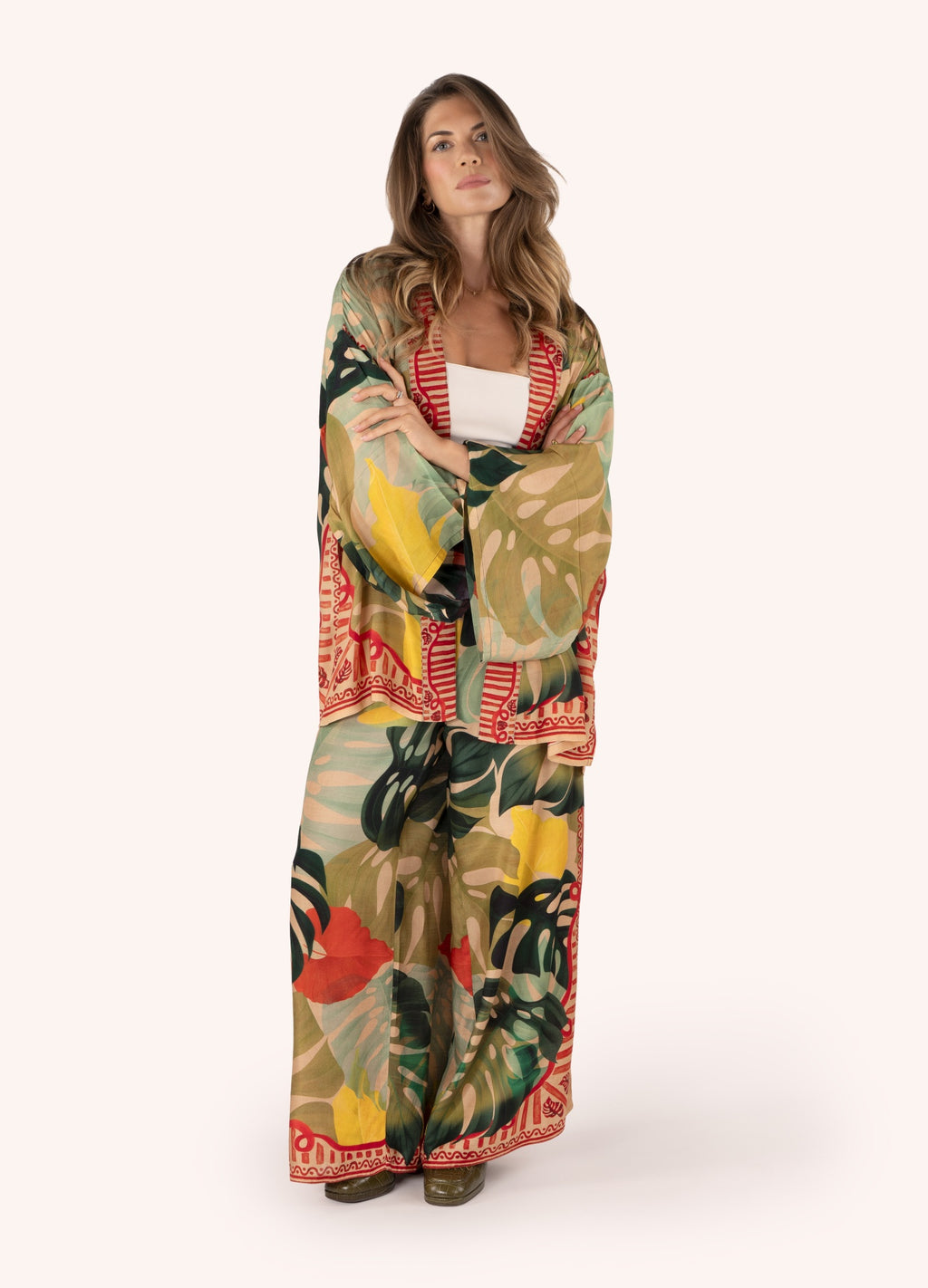 Mulher usando conjunto com kimono e calças largas estampadas com folhas tropicais