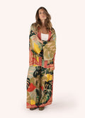 Mulher usando conjunto com kimono e calças largas estampadas com folhas tropicais