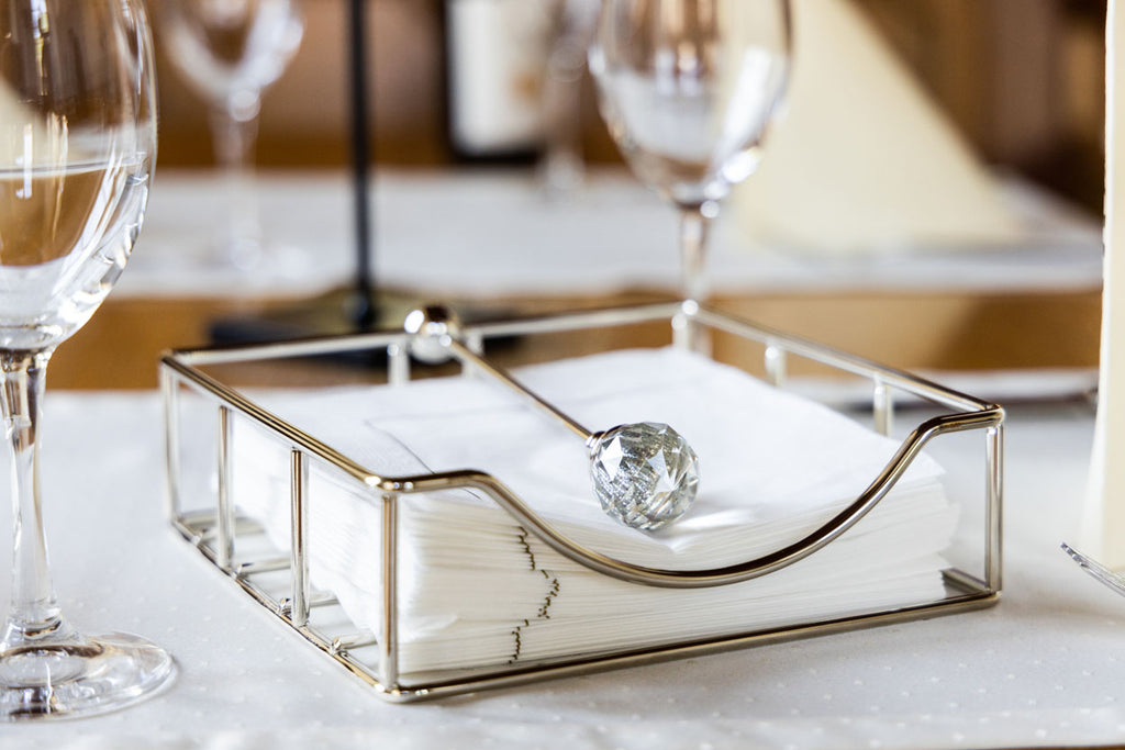 Suporte de metal para guardanapos com puxador decorativo em mesa branca