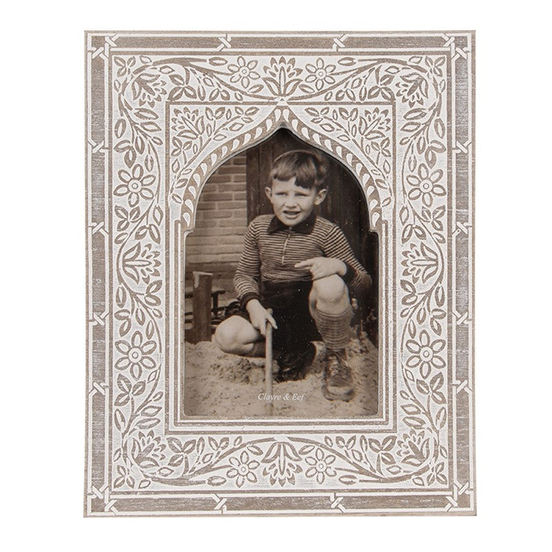 Fotografia antiga de rapaz num quadro decorativo branco com padrão floral