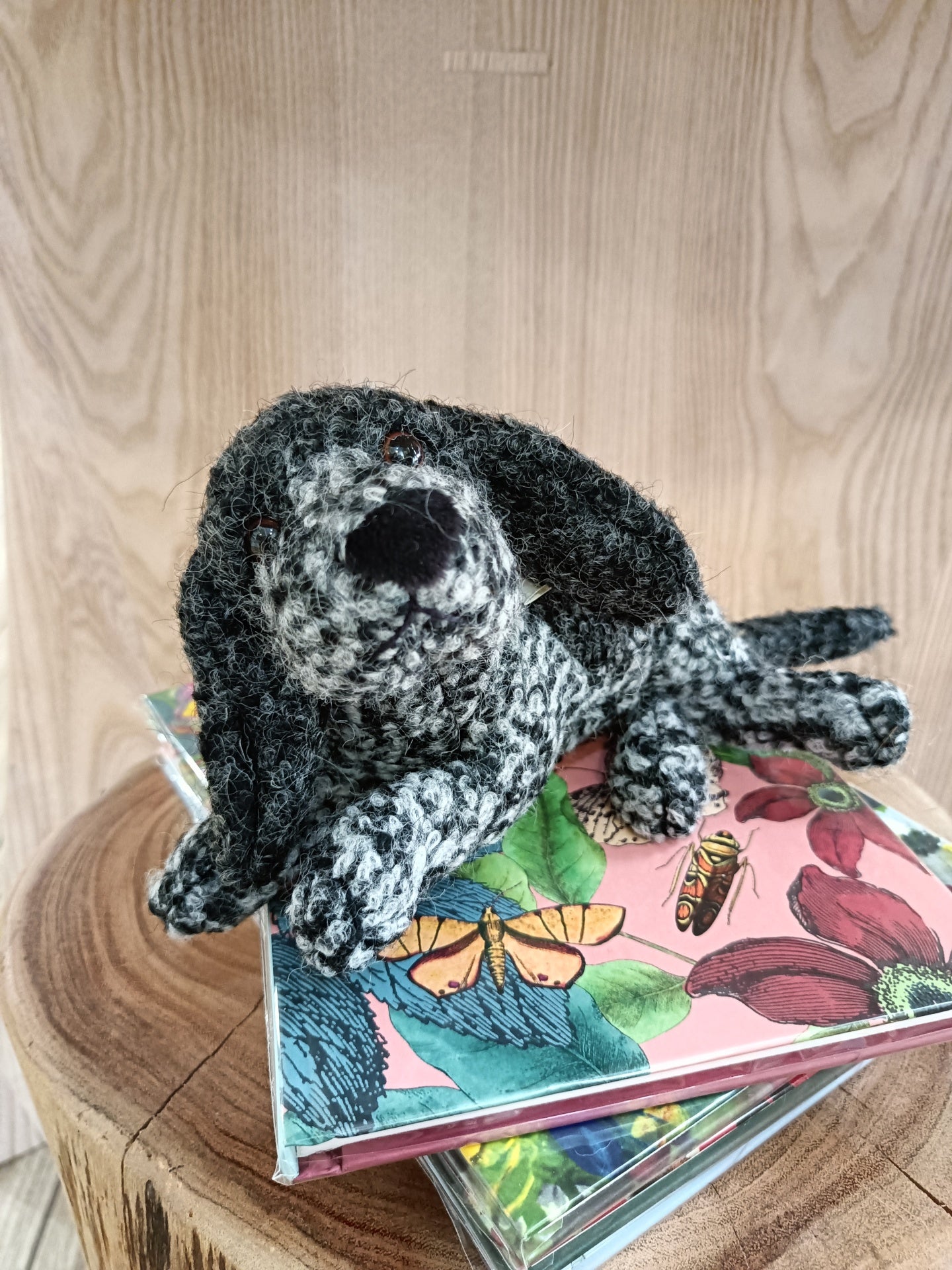Peluche de cão cinzento e preto sobre livros coloridos numa superfície de madeira