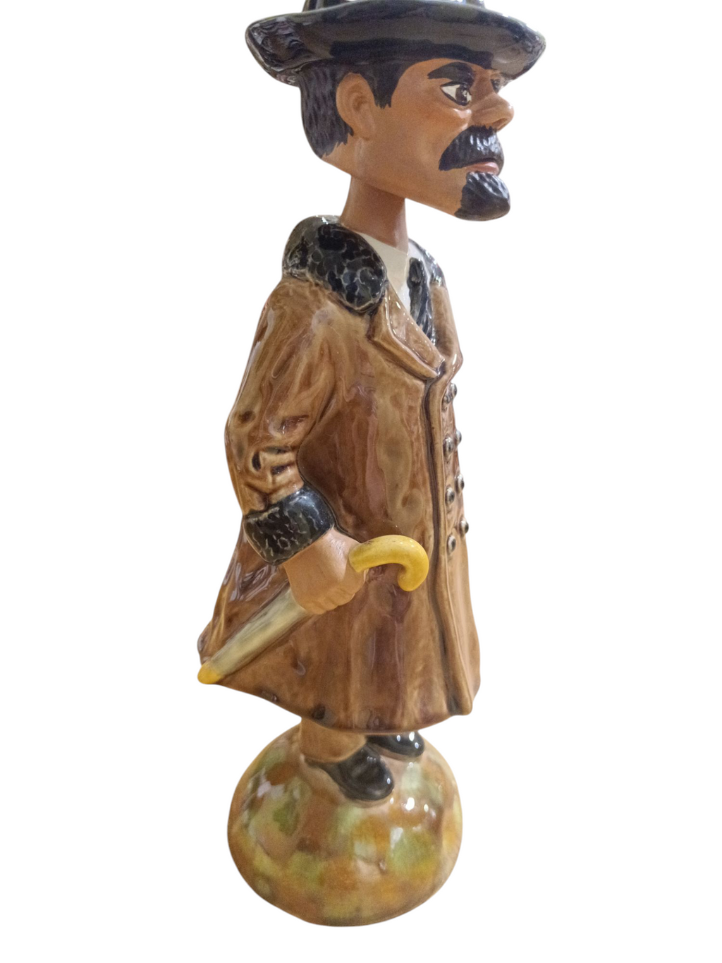 Estatueta cerâmica de homem com casaco castanho e chapéu, segurando bengala amarela