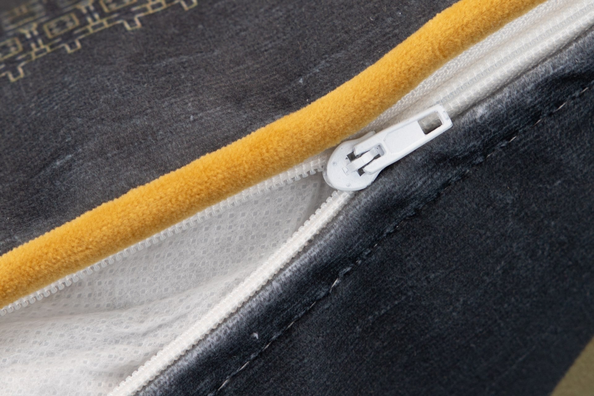 Fecho éclair branco numa capa de tecido amarelo e cinzento escuro com textura
