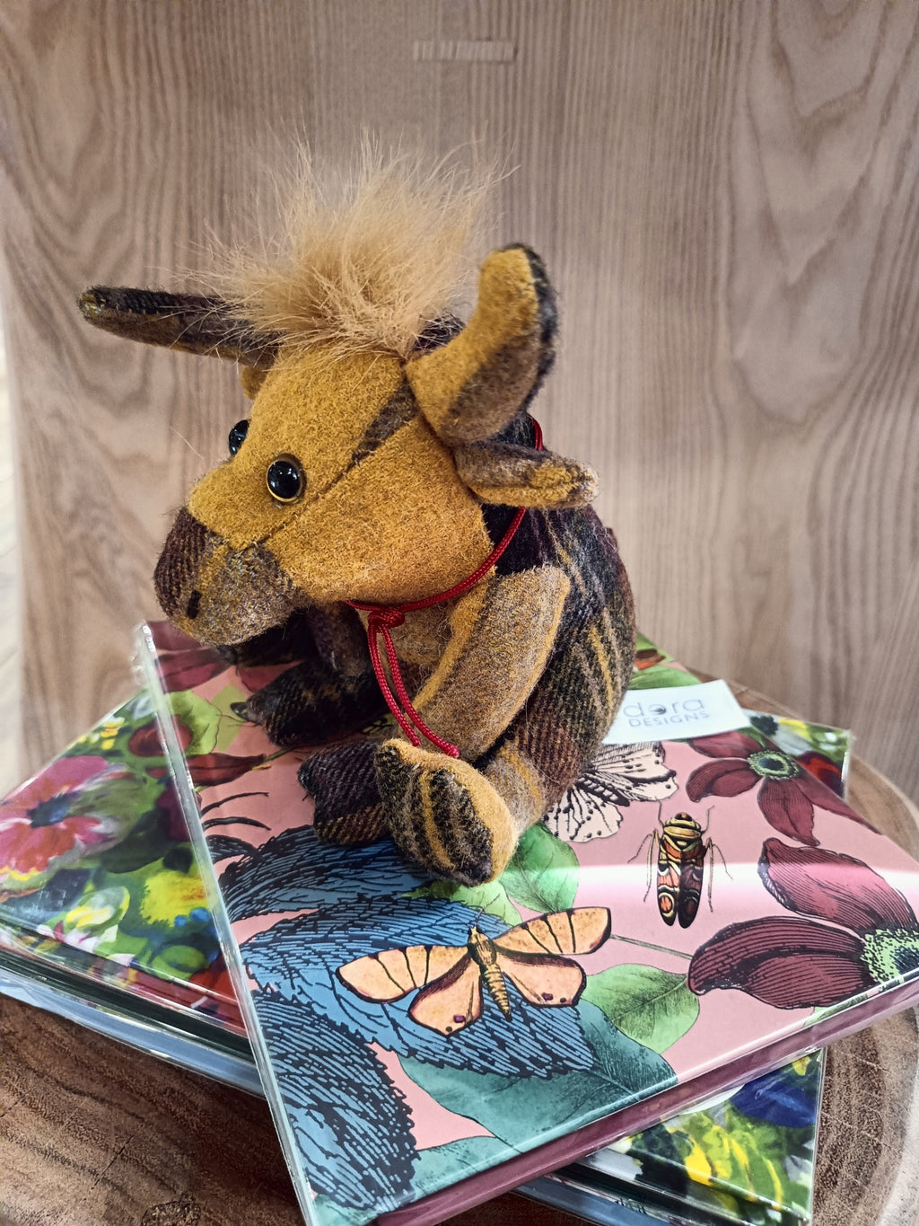 Boneco de tecido animal sobre capas coloridas com padrão floral e borboletas