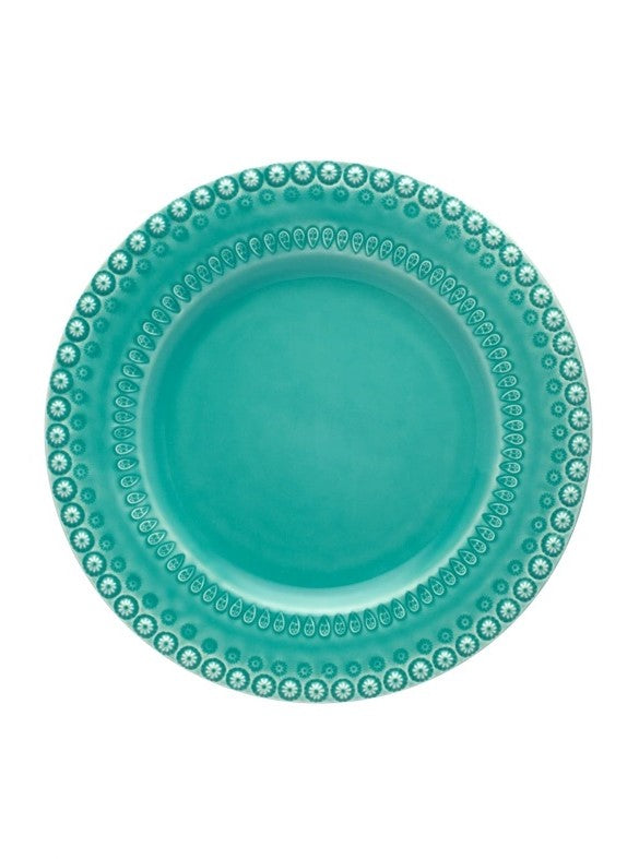 Prato redondo azul-turquesa com padrões decorativos brancos na borda.