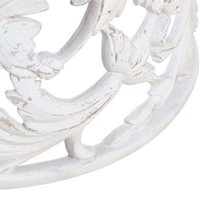 Detalhe de objeto decorativo branco envelhecido com padrões florais e folhas