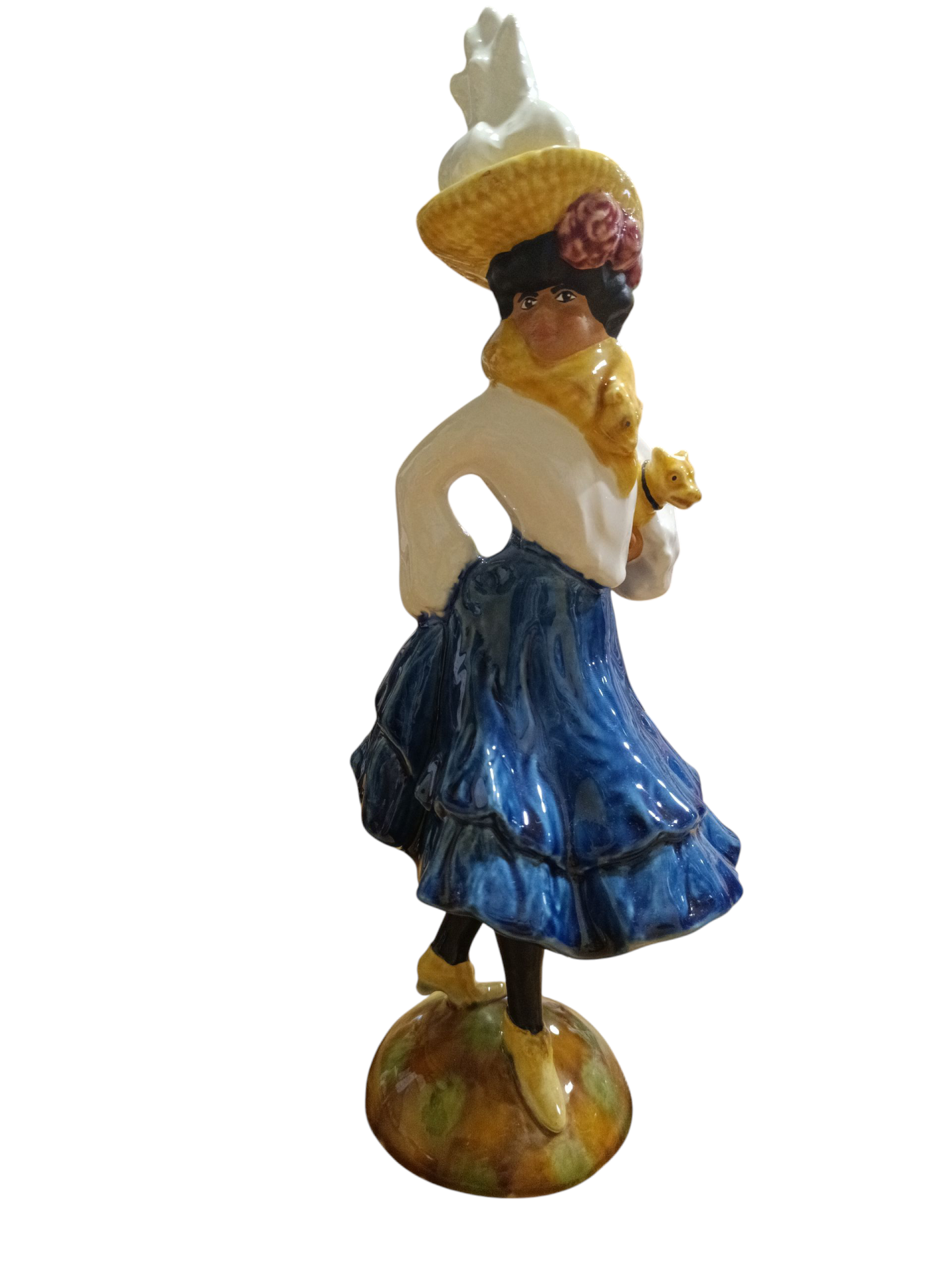 Figura decorativa de cerâmica com mulher de saia azul e chapéu amarelo segurando pássaros.
