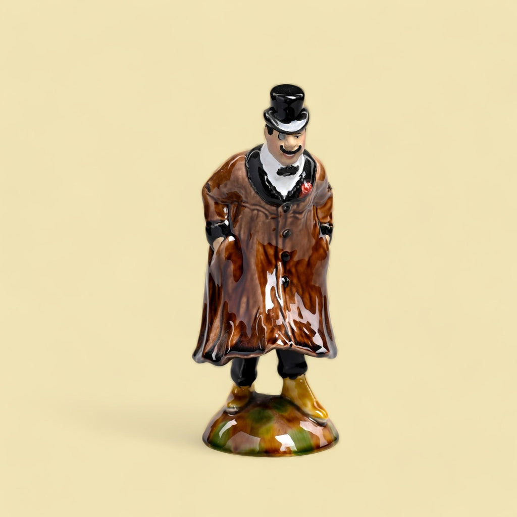 Figurina de porcelana de homem com cartola e casaco castanho