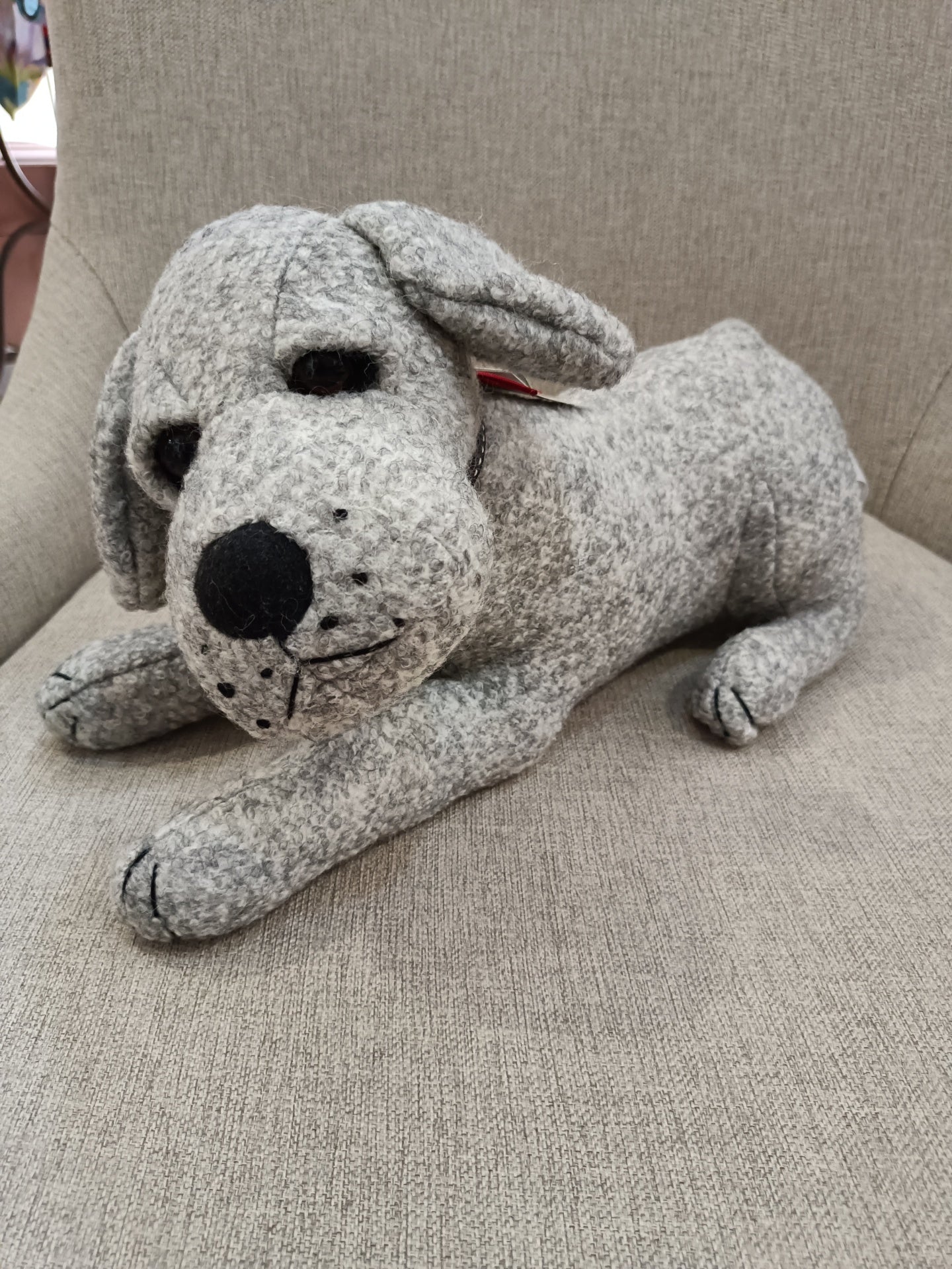 Pelúcia de cachorro cinzento sobre cadeira bege