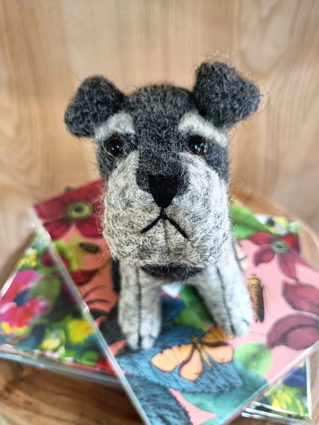 Boneco de cão em feltro cinzento e branco sobre cadernos florais