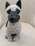 Boneco de pelúcia cinza de cão sentado sobre tecido cinza claro