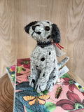 Boneco de cão Dalmatian tecido cinzento com manchas pretas sobre caixa floral colorida