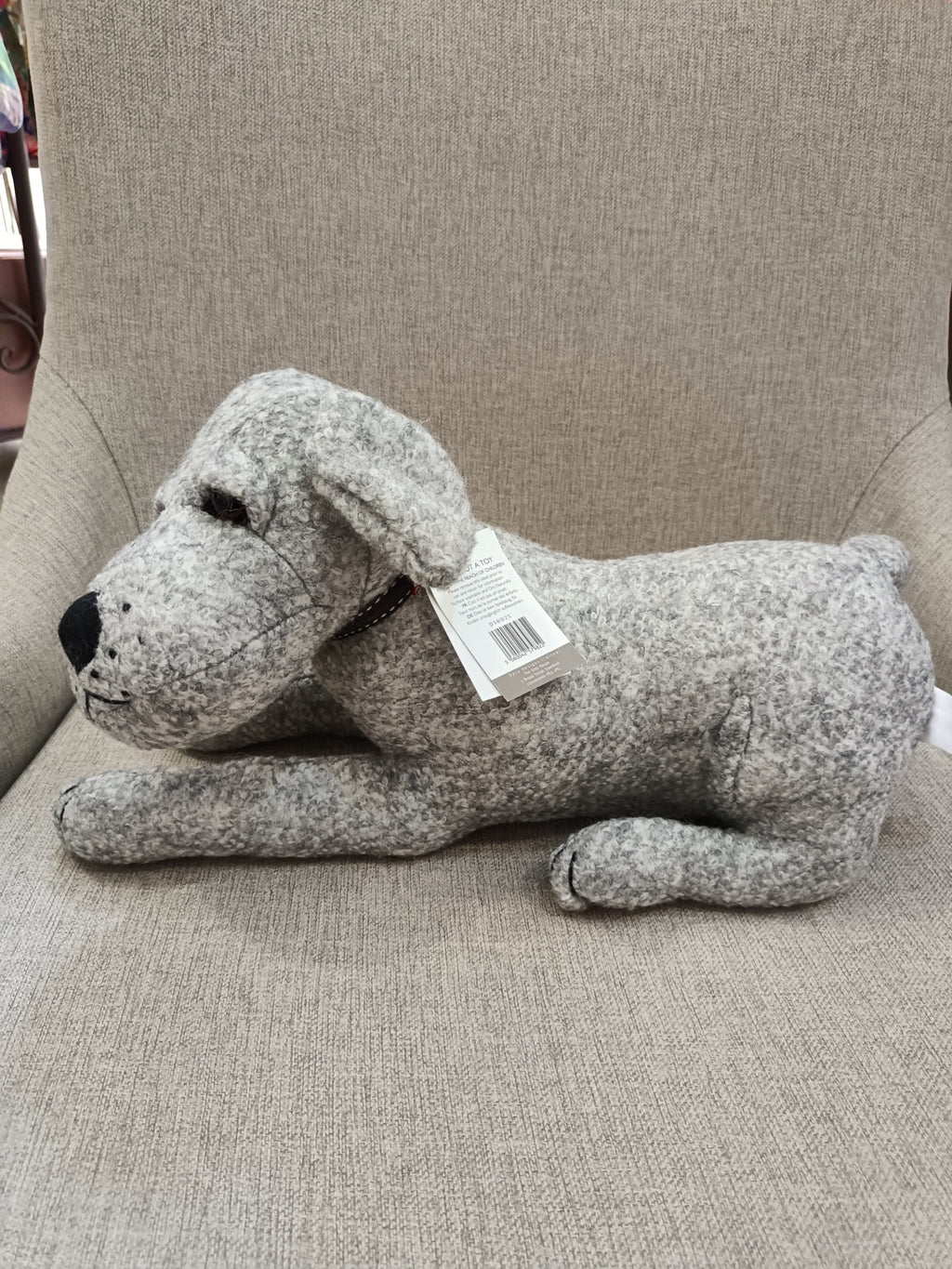 Boneco de peluche em forma de cão cinzento deitado num sofá