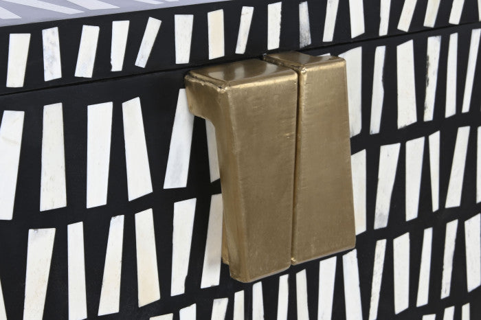 Fechadura dourada em porta com padrão geométrico preto e branco