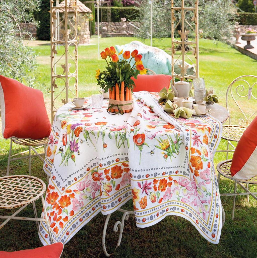 Mesa de jardim com toalha de flores coloridas e cadeiras com almofadas laranja