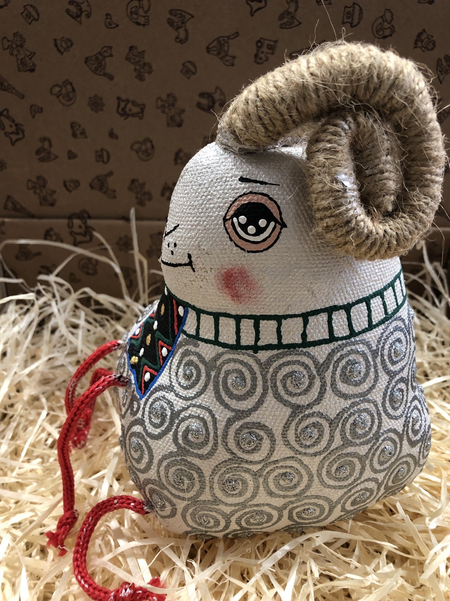 Boneco decorativo de tecido com chifres e padrão de espirais cinzentas