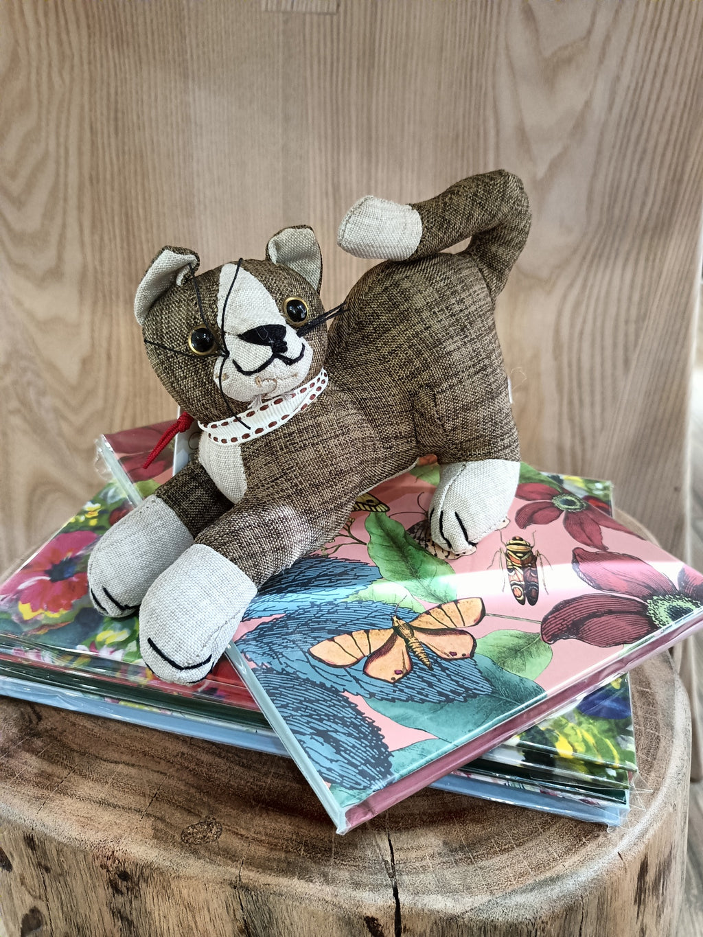 Peluche de gato castanho sobre cadernos coloridos em vaso de madeira