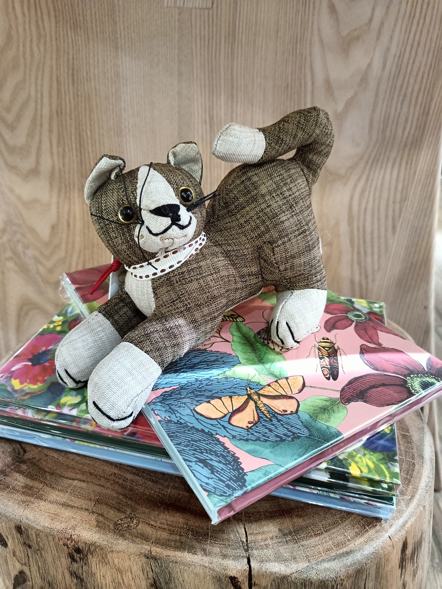 Peluche de gato castanho sobre cadernos coloridos em vaso de madeira