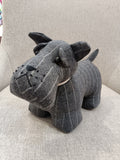 Boneco cão em tecido cinzento riscado numa cadeira bege claro