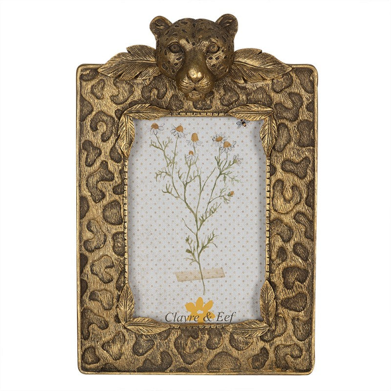 Moldura dourada com cabeça de leopardo em relevo e padrão de pele, contendo imagem de flores secas