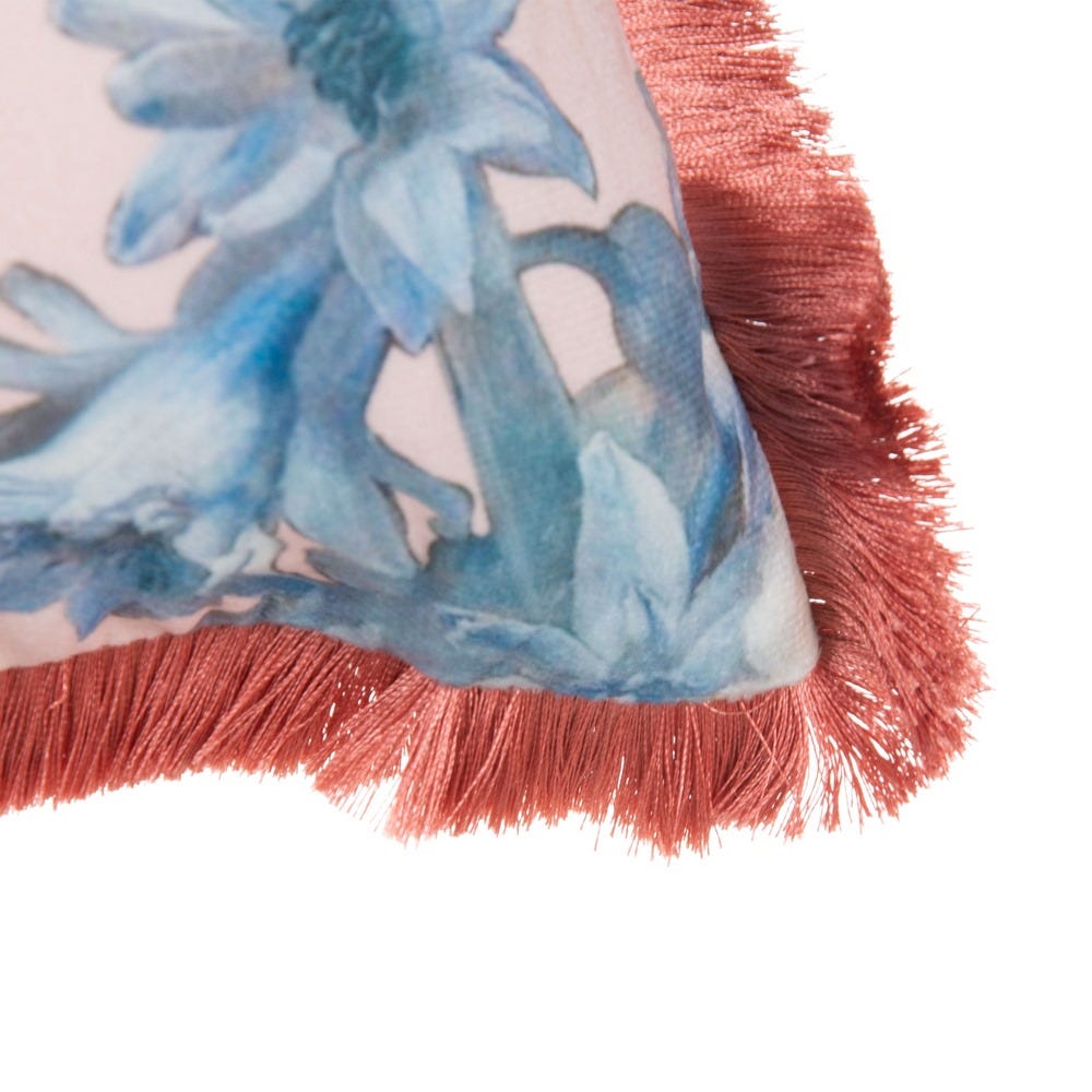Canto de almofada decorativa com estampa floral azul e franja vermelha