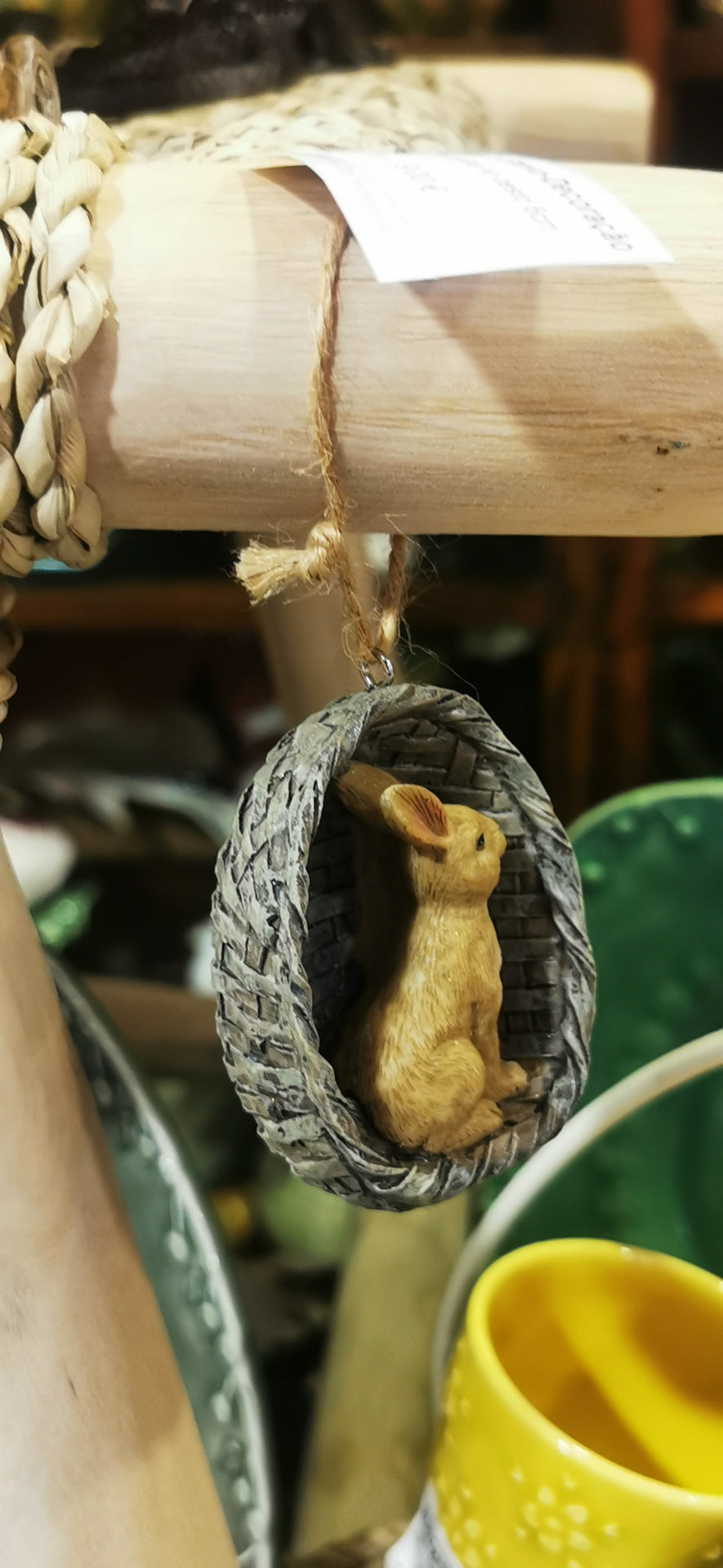 Pendente decorativo com coelho dentro de cesta trançada pendurado em estrutura de madeira
