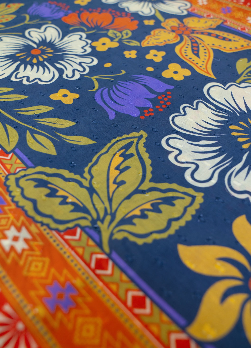 Tecido com padrão floral colorido e borda geométrica em cores vivas