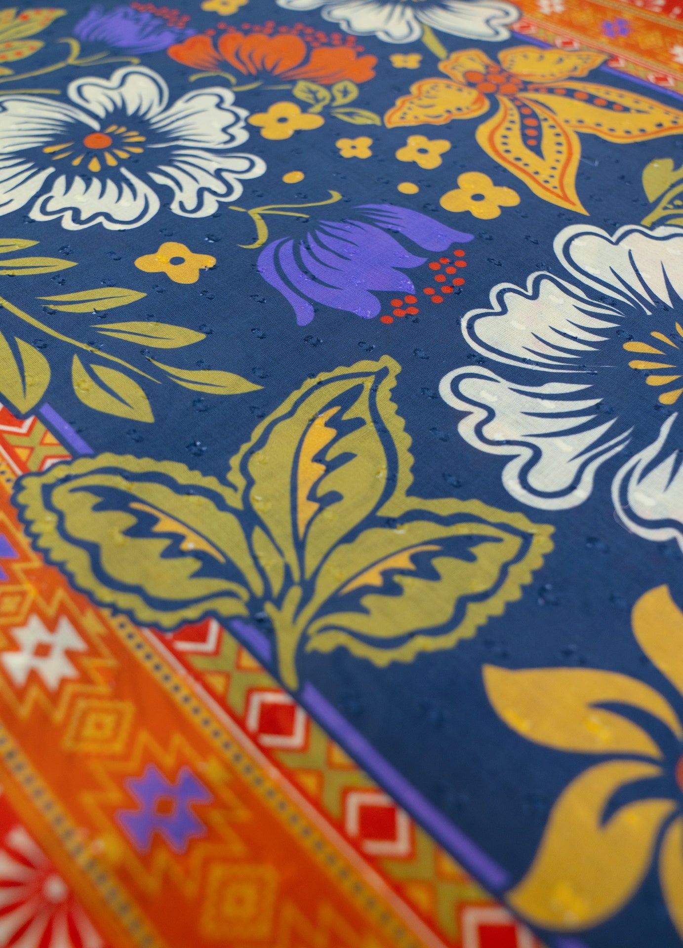 Tecido com padrão floral colorido e borda geométrica em cores vivas