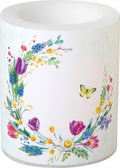 Vela decorativa branca com padrão floral colorido e borboleta