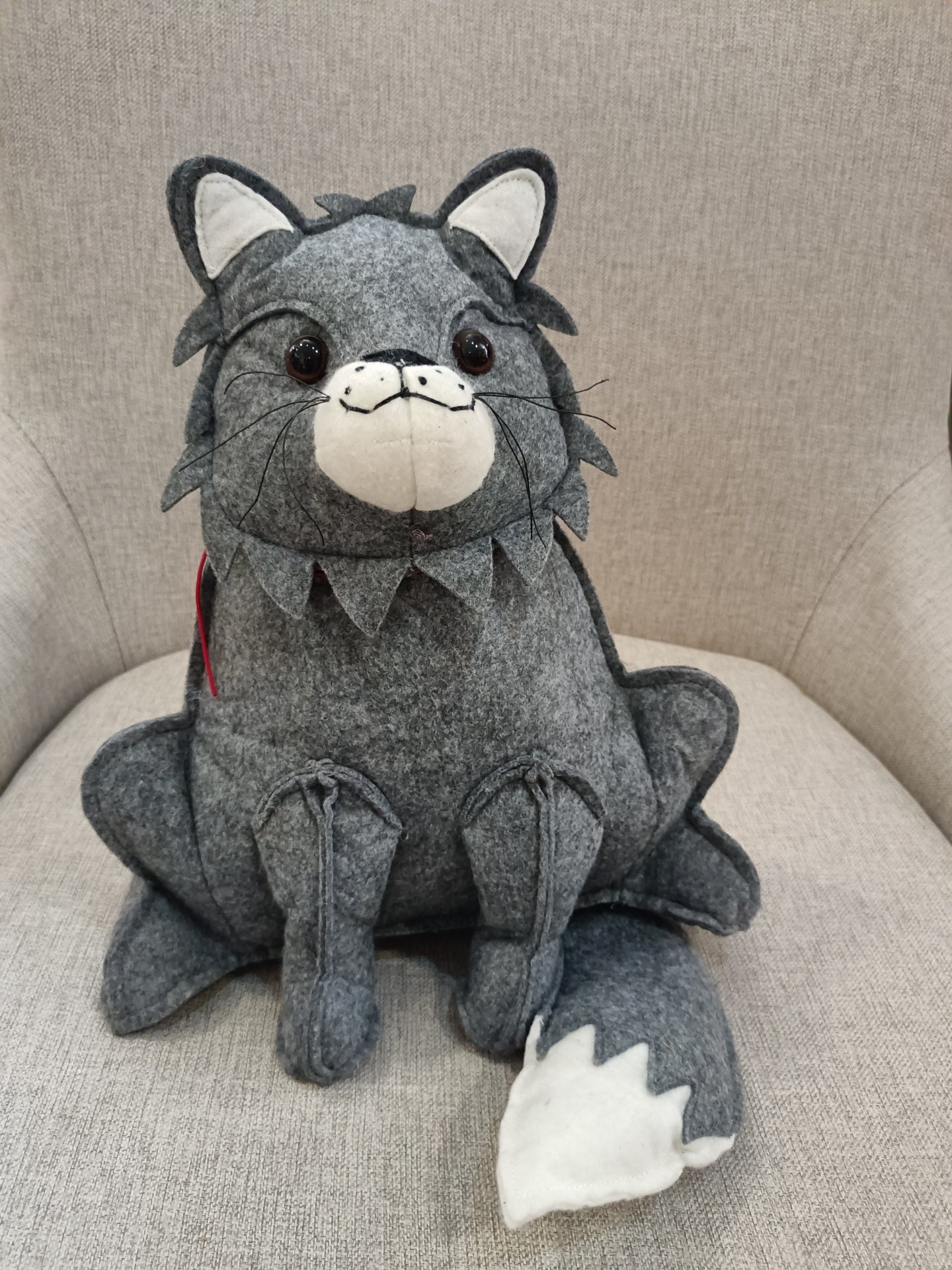 Pelúcia de lobo cinzento sentada numa cadeira cinzenta