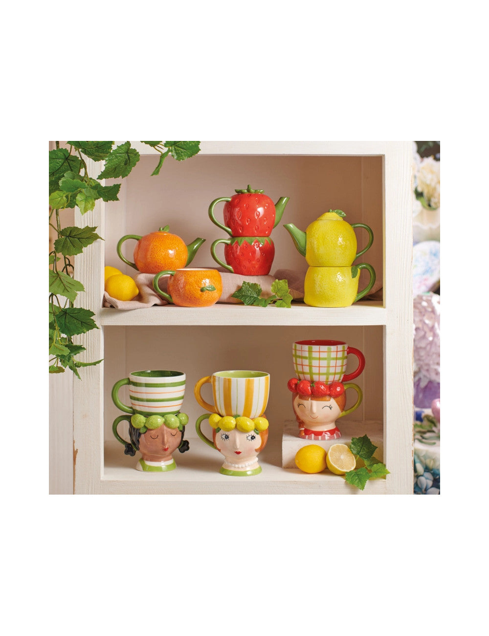 Canecas e bules cerâmicos decorativos em forma de frutas e cabeças femininas numa estante branca