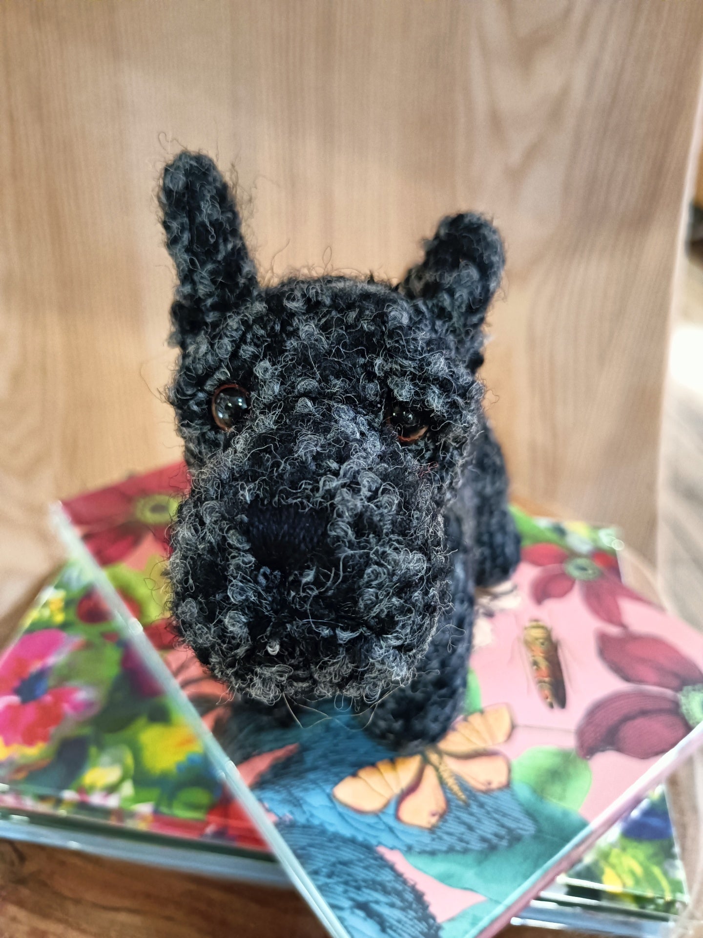 Pelúcia de cão preto feita de fio felpudo sobre cadernos coloridos com padrões florais