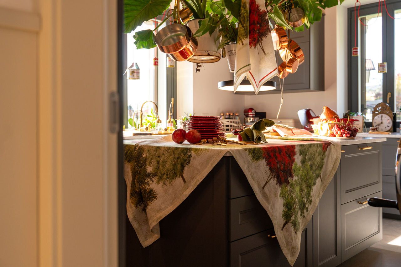 Toalha de mesa com padrão verde e vermelho sobre bancada de cozinha cinzenta com elementos decorativos.