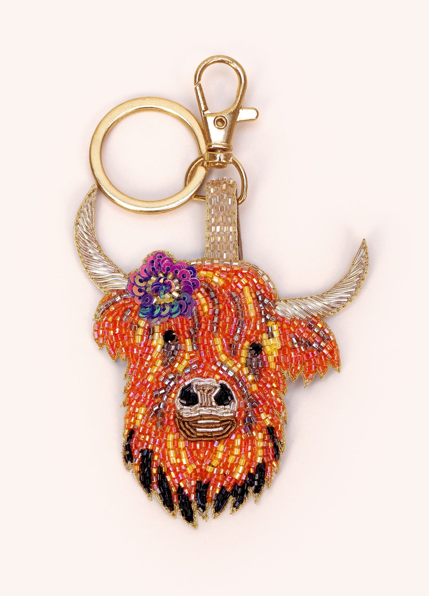 Porta-chaves com cabeça de vaca colorida em miçangas e detalhe dourado.