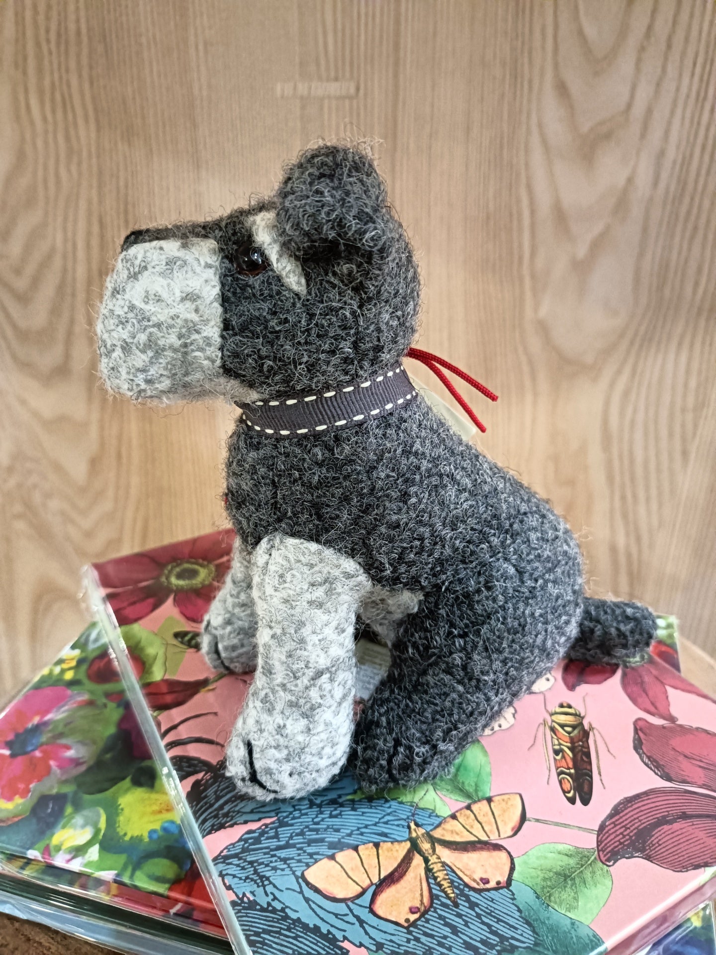 Pelúcia de cão cinzento e branco com coleira preta sobre caixas coloridas