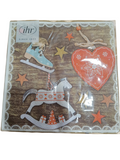 Guardanapo de papel natalício com desenhos de patins, coração e cavalo de balanço sobre fundo madeira