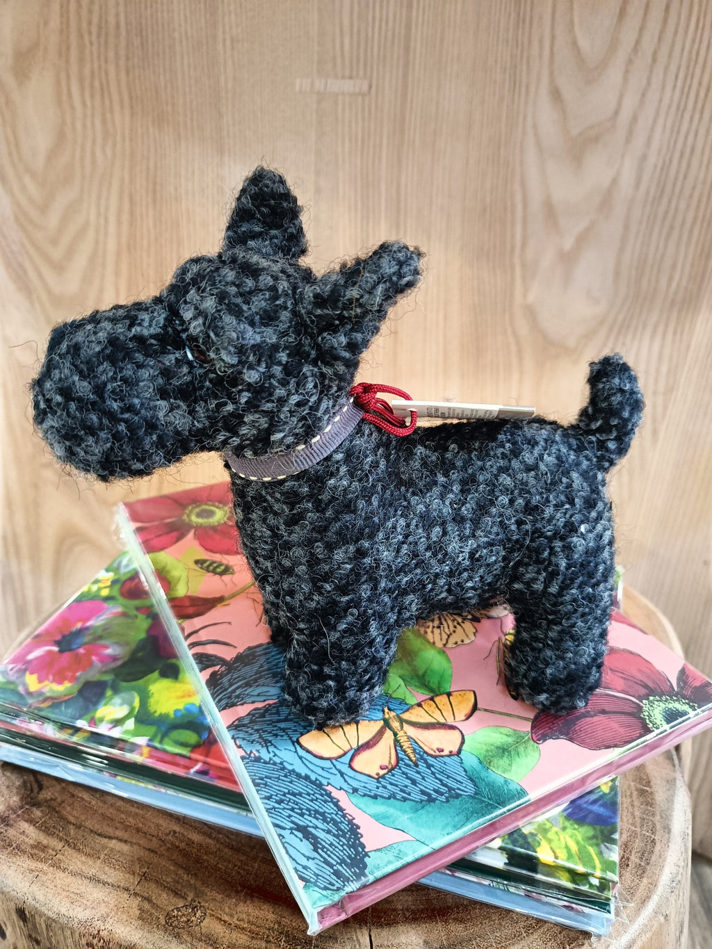 Figura de cão em tecido cinza sobre caixas coloridas com padrões florais