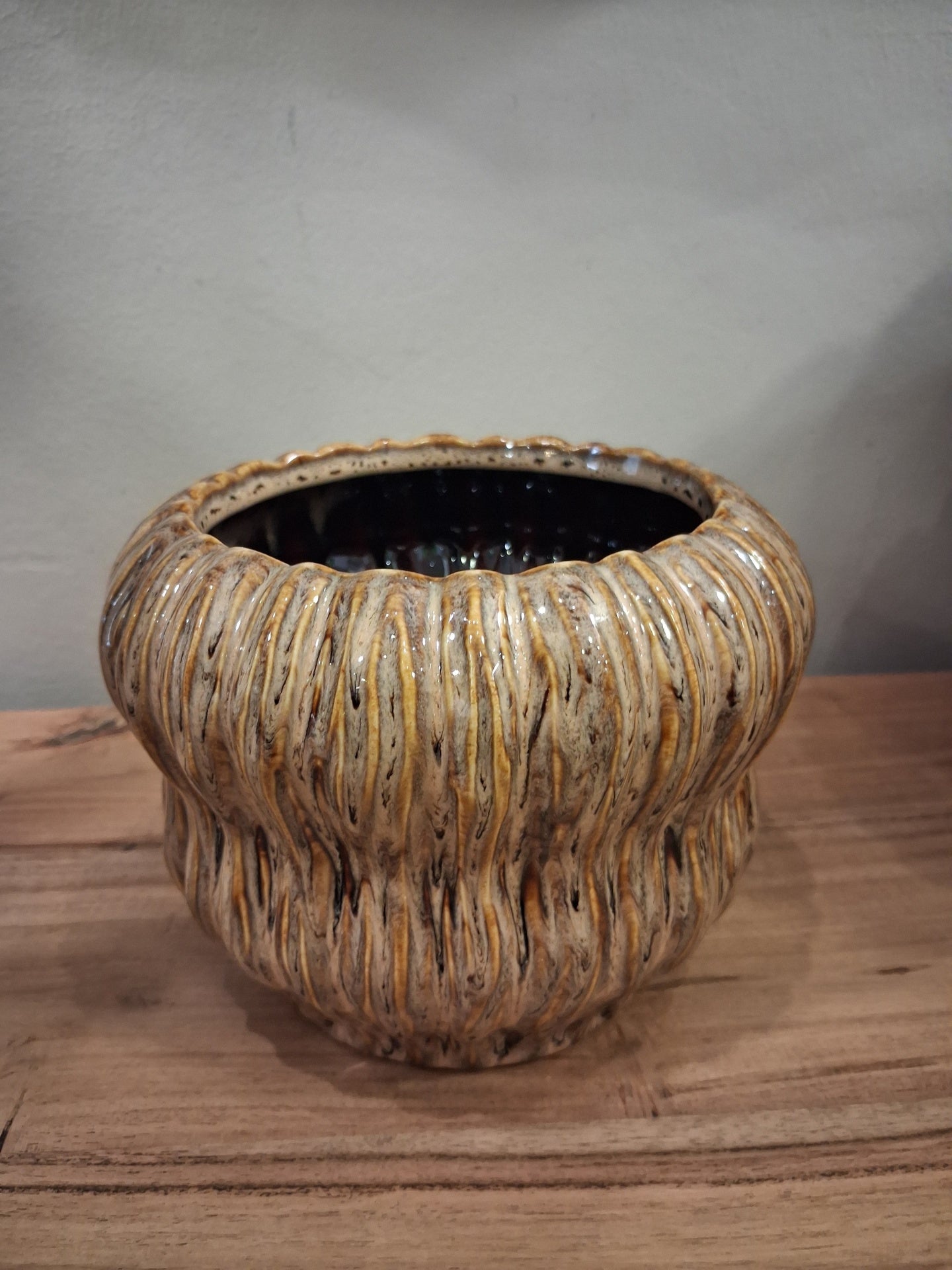Vaso de cerâmica castanho texturizado com interior preto em superfície de madeira