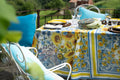 Mesa de exterior com toalha estampada de girassóis e cadeiras com almofadas azuis