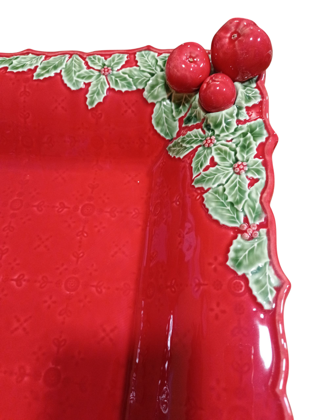 Prato decorativo vermelho com folhas verdes e frutos vermelhos no canto