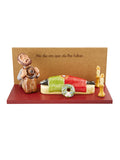Figura decorativa com homem ajoelhado, vela, campa e texto em fundo madeira