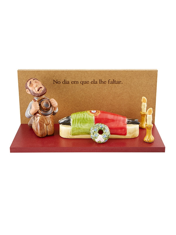 Figura decorativa com homem ajoelhado, vela, campa e texto em fundo madeira