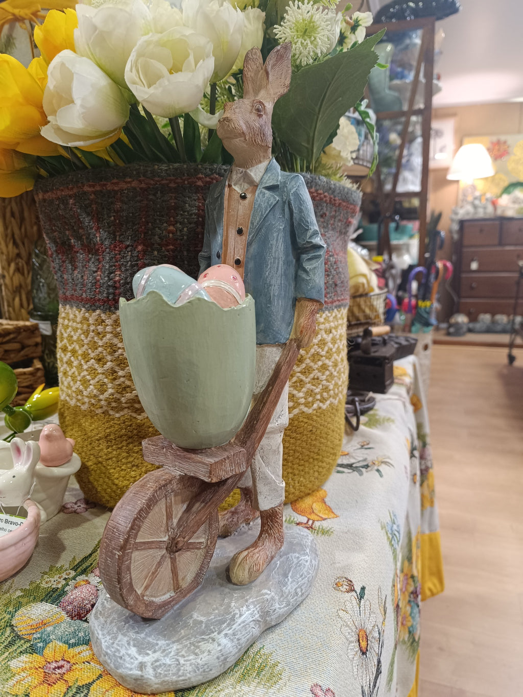 Estátua decorativa de coelho empurrando carrinho com ovos coloridos feita em madeira ou resina