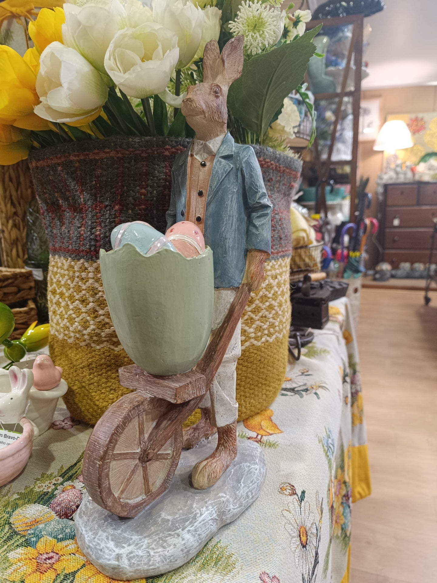 Estátua decorativa de coelho empurrando carrinho com ovos coloridos feita em madeira ou resina