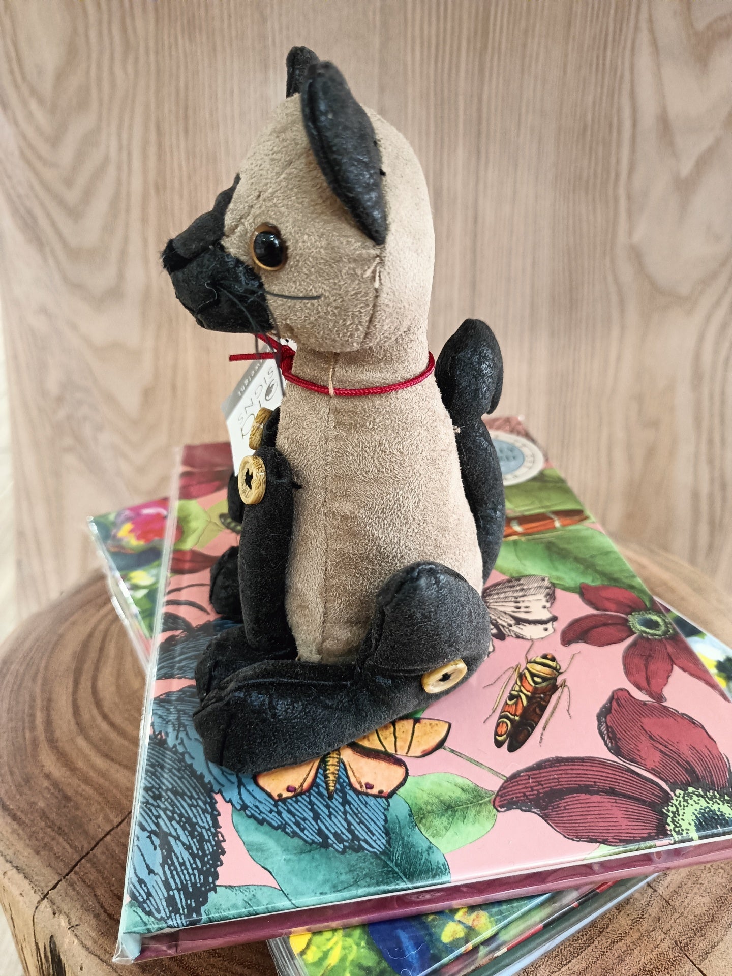 Boneco de peluche de cão com detalhes pretos sentado sobre agendas floridas sobre madeira