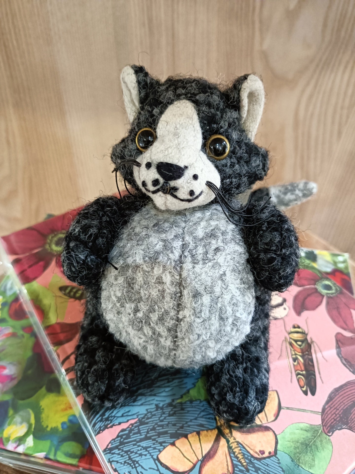 Boneco de peluche de lobo cinzento e branco sobre livro colorido com padrão floral
