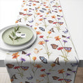 Toalha de mesa branca com padrão colorido de borboletas e flores.